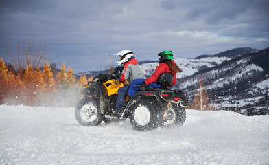 Portrait of man and woman riding on offroad four-wheeler ATV. Concept of active leisure and winter...