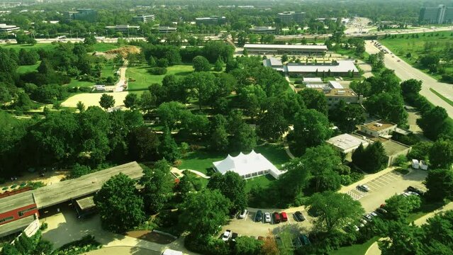 A drone shot of a beautiful the morton arboretum along with the busy road outside of it. Beautiful typical countryside summer landscape 4k aerial