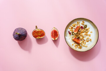 Eine Frühstück Schüssel mit Müsli, Joghurt und Feigen auf einem rosa Hintergrund. Modern,...