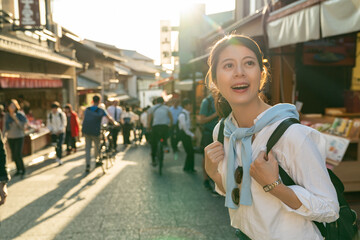 backlit shot of happy asian Japanese female traveler having fun looking around at crowded Ninenzaka...