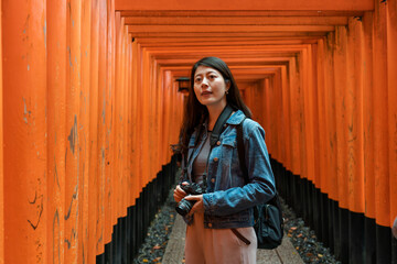 amazed asian chinese girl tourist carrying camera and looking into distance while visiting the red...