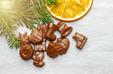 christmas dark chocolates on gray surface golden bokeh lights.different shapes chocolates,star,toy train,santa claus,deer,fir tree,gift,christmas wreath circle on door,skate,bells and others.tasty 