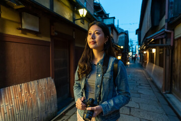 amazed asian Japanese girl photographer looking at local geisha houses while exploring hanamikoji street in gion Kyoto japan at night