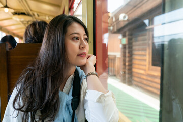 asian Japanese woman passenger propping face and looking out of window as the Arashiyama Mountains...