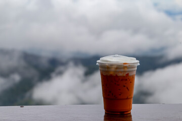 Close up photo of iced milk tea in plastic glass on table and blurred nature background.