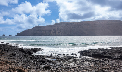 Cliffs and pristine beaches on the island of La Graciosa, with the Risco de Famara in the background, Canary Islands. 