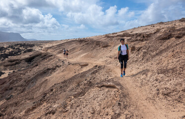 Young woman hiking along the cliffs and unspoiled beaches on the island of La Graciosa, Canary Islands. 