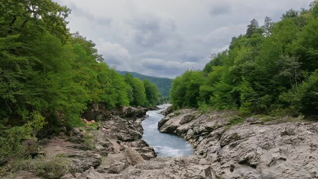 Aerial view of Mountain river and road. Flying over a mountain gorge. Slow motion video