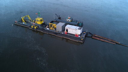 A River Dredger on a river during a misty dusk. Aerial side view.