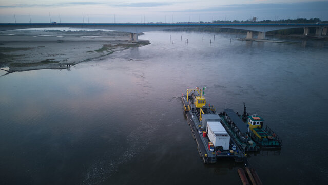 A River Dredger on a river during a misty dusk. Aerial side view.