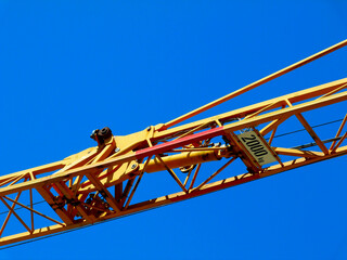 yellow steel truss crane boom closeup. clear blue sky. building construction industry concept. lifting and hoisting device. isolated machine part. painted yellow and red metal members. building trade.