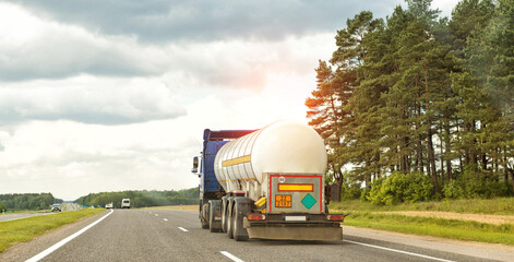 A truck with a semi-trailer tank transports a dangerous cargo of liquefied gas. The concept of transportation of flammable goods. Copy space for text, industry - obrazy, fototapety, plakaty