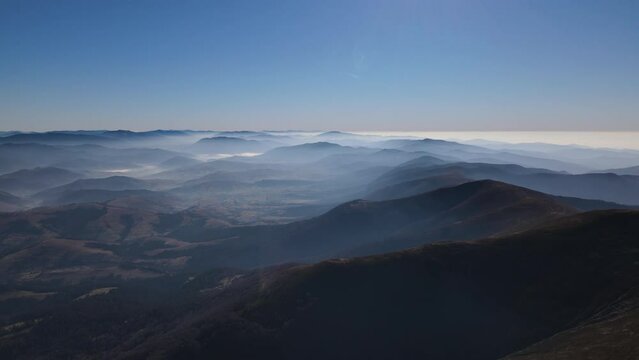 Scenic aerial view of the Carpathians in early autumn, mountain range covered with morning fog on the horizon