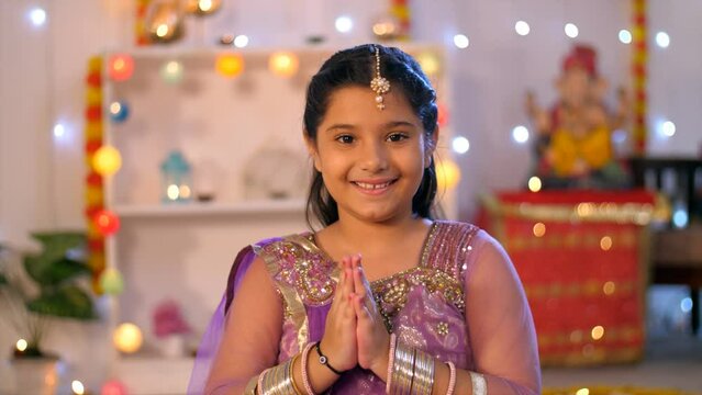 Diwali greetings by young Indian girl - Namaste greetings on Diwali festival  Hindu religion  auspicious occasion. An Indian child greeting in a traditional Indian Namaste pose - colorful backgroun...