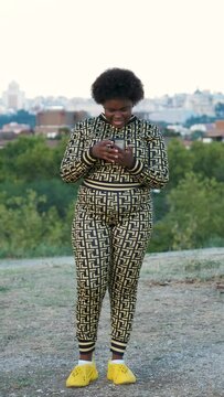 Young Equatoguinean woman laughing while using the smartphone at street.