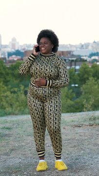 Young Equatoguinean woman laughing and talking on the smartphone at street.