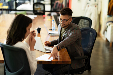 Businessman gives businesswoman dismissal contract to sign.