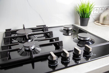 Modern gas hob with cast iron grate against white porcelain tiles on the wall. Kitchen area. Copy...