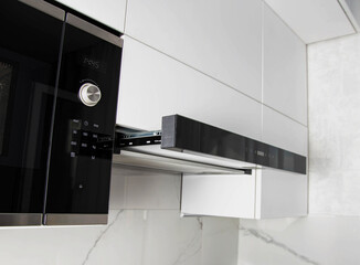 Modern household kitchen appliances. Black retractable telescopic hood in the kitchen. Interior