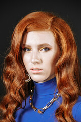 red-haired girl in blue clothes with bright makeup and gold jewelry