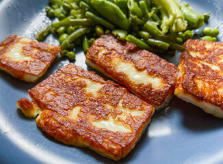 Grilled halloumi cheese on a plate with green beans.
