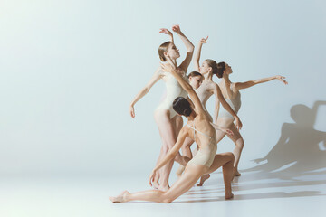 Group of young women, ballerinas dancing, performing isolated over grey studio background. Tenderness, attraction, grace - obrazy, fototapety, plakaty