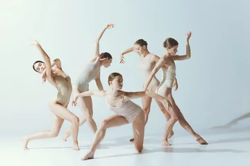 Fototapete Tanzschule Gruppe junger, zarter Mädchen, die isoliert vor grauem Studiohintergrund tanzen. Ballettschule, Tanzpädagogik