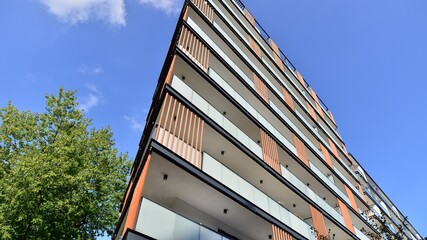 Modern residential building with new apartments in a green residential area. Eco architecture. Green tree and new apartment building. The harmony of nature and modernity.