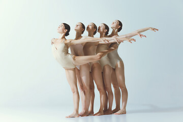 Group of young girls, ballet dancers performing isolated over grey studio background. Tender pose.