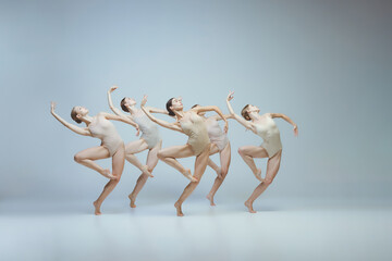 Group of young girls, ballet dancers performing, posing isolated over grey studio background....