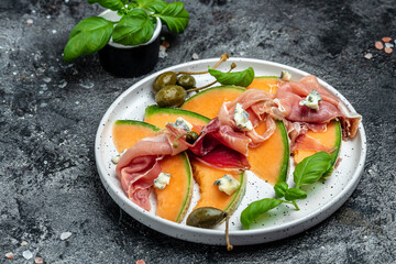 Appetizer, melon with jamon and Basil. Antipasti, Italian food. Top view on dark table. Long banner format. top view