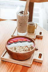 Delicious healthy breakfast, strawberry smoothie bowl with granola, fruit, chia seeds and coconut, an aesthetic shot on a light background.