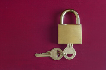 A gold padlock with a key inside and another key attached to it on a colorful studio background...