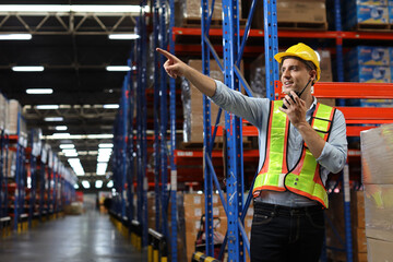 Fototapeta na wymiar Caucasian warehouse workers with hardhats and reflective jackets using tablet, walkie talkie radio and cardboard while pointing something in retail warehouse logistics, distribution center