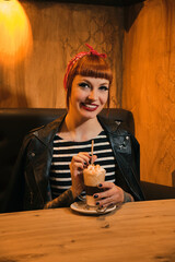 Portrait of a redhead, attractive and smiling woman looking at camera posing with a coffee with cream.