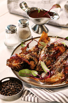 Baked sea bass with herbs and sauce, three fish on a platter, homemade table setting, cozy and warm