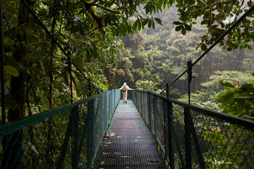 Ancient man walking in a hanging bridge in the rainforest
