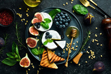 A plate with Brie cheese, with honey and figs. On a concrete background. Top view.