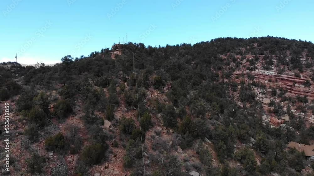 Poster trees on mountainside with power lines • spruce trees and red rocks • aerial drone shot in horizonta