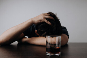 Alcoholism, depressed man sleep on table while drinking alcoholic beverage with glass of whiskey