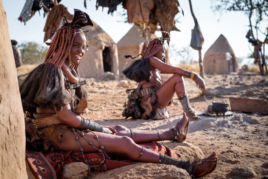 Himba women sitting outside their huts in a traditional Himba village near Kamanjab, northern Namibia, Africa.