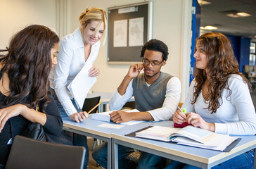 Teenage Students: Teaching Aid. A teacher helping her students understand the subject in class. From a series of related images.