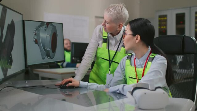 Diverse female engineers discuss 3d detail model working on computer in factory office