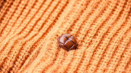 Botón marrón en jersey de lana naranja