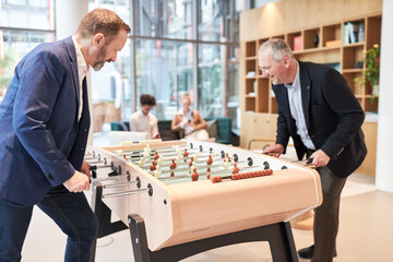 Two business people have fun playing table football