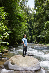 A boy on top of a rock in the middle of a river