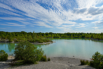 Fototapeta na wymiar View of the Dyckerhoff lake in Beckum. Quarry west. Blue Lagoon. Landscape with a turquoise blue lake and the surrounding nature. 