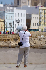 Fototapeta na wymiar Vieil homme prenant une photo de la cathédrale de Cadix
