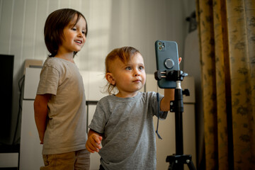 Two blogger brothers record videos on their phone using a tripod. Children and modern technologies