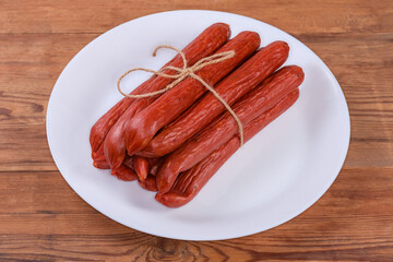 Long thin smoked sausages on dish on rustic table